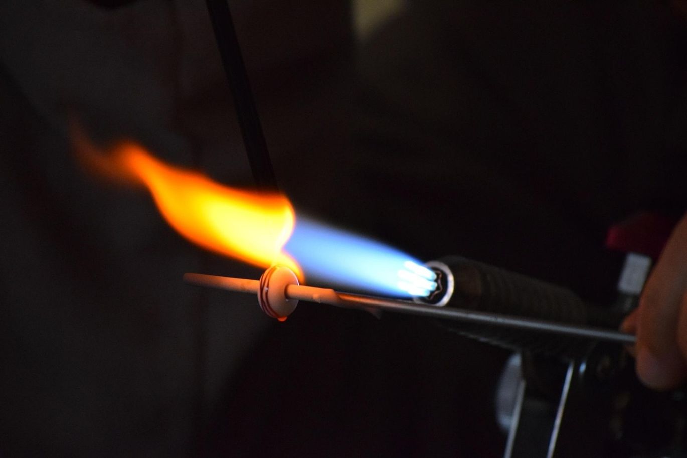 Close-up of a technician carefully extracting rhodium from a catalytic converter component during a refining process.