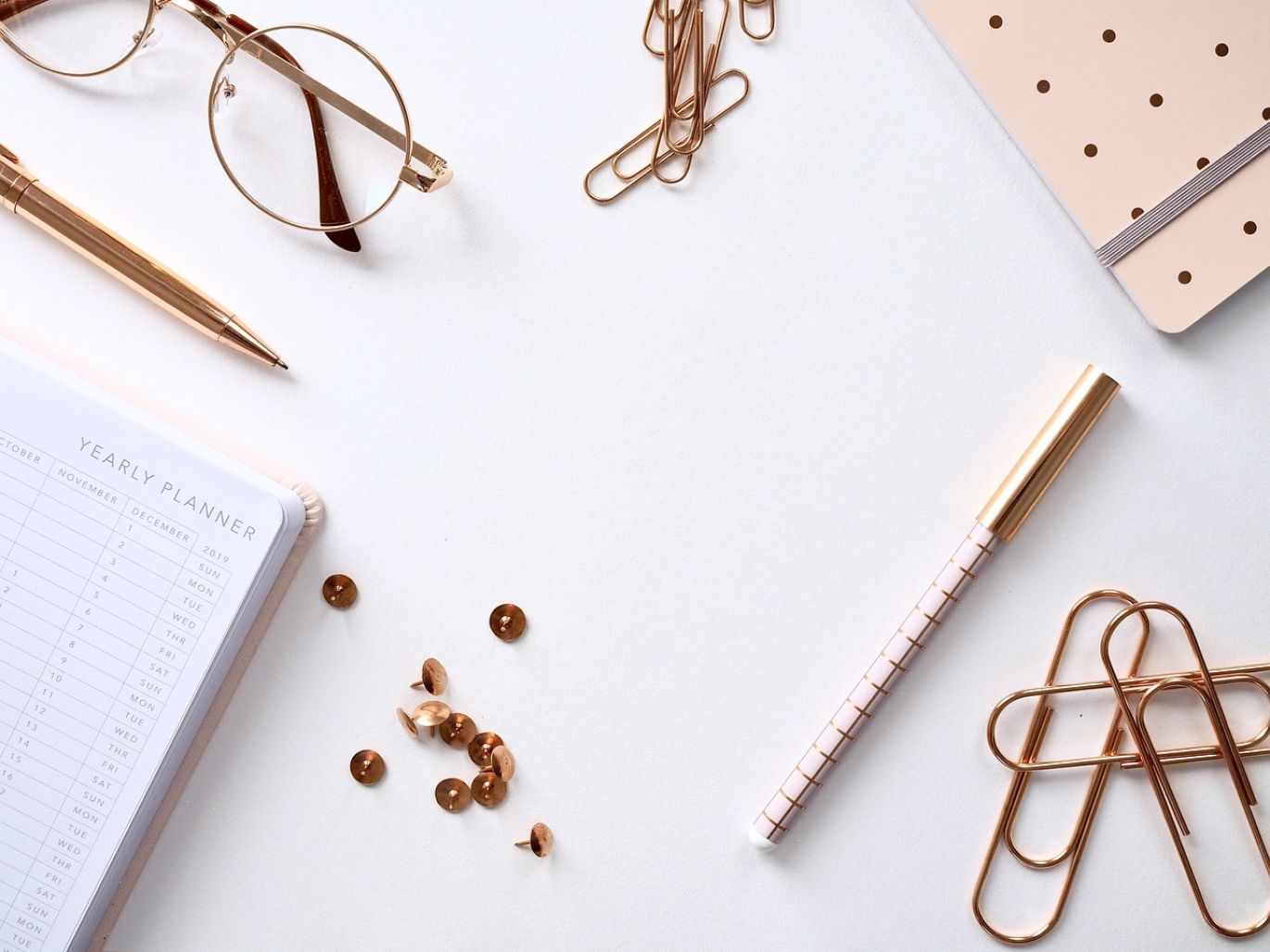 Close-up of various Rose Gold Jewelry Making Supplies, including wires, sheets, and findings, displayed on a clean surface.