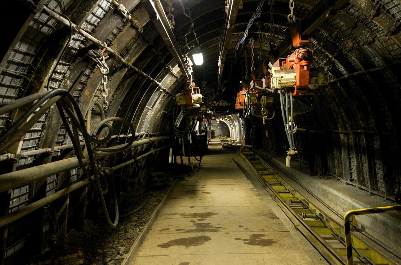 Close-up of heavy-duty drill machinery performing underground drill and blast operation for mineral extraction.